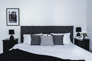 Restful retreat with a large bed, tufted headboard, and bedside tables featuring lamps and plants.