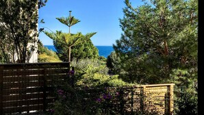 Un jardín con vista al mar, una cerca y un edificio de techo rojo.