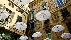 A building facade with multiple white umbrellas hanging from the balconies.