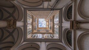 A grand architectural interior with a central skylight, arched windows, and classical columns.