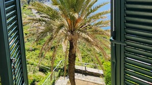 Un balcón con vista a una palmera y montañas.