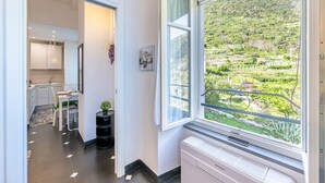 Una cocina moderna con armarios blancos, un comedor con mesa y sillas, y un amplio ventanal con vistas a un paisaje verde.