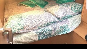 A small, enclosed space with a bed and a chair, featuring a patterned bedspread and green pillows. - Paradise Boat & Breakfast (Salerno)