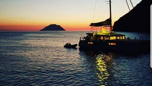 A boat docked at sunset with a view of a distant island and a small boat nearby. - Paradise Boat & Breakfast (Salerno)
