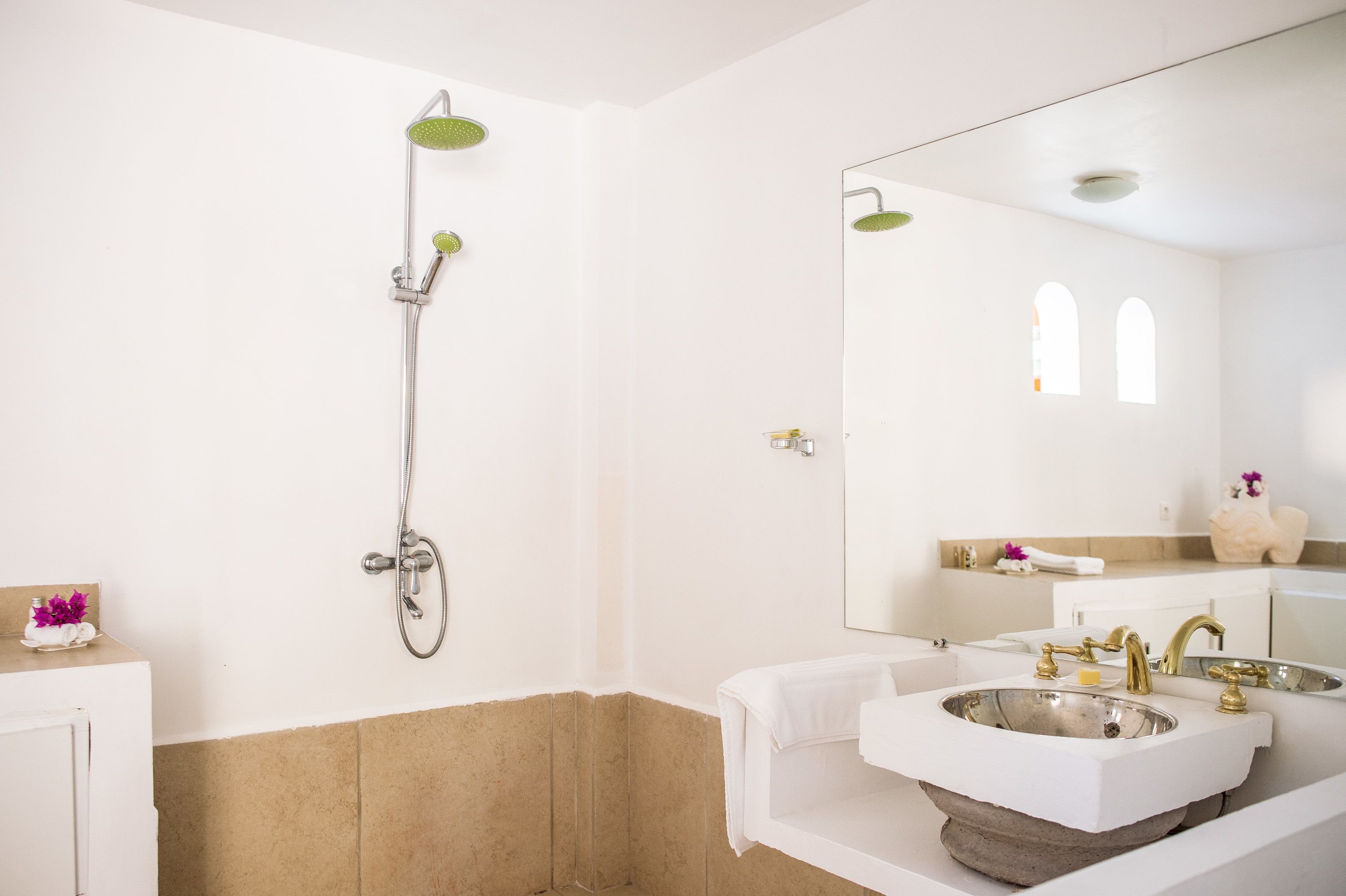 A bathroom with a large mirror, a shower, and a sink.