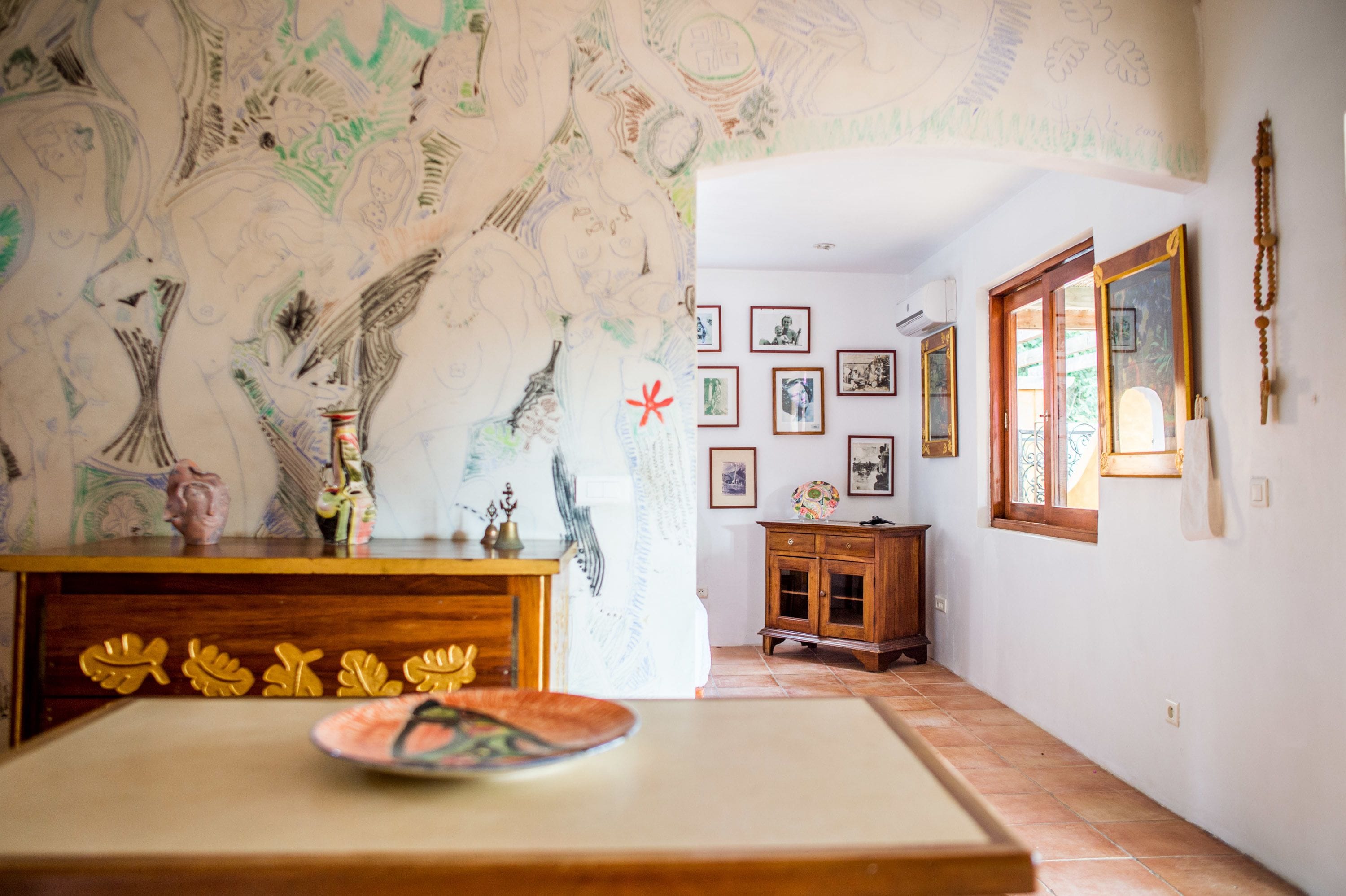 Una habitació amb un armari de fusta, una paret amb dibuixos i quadres a la paret.