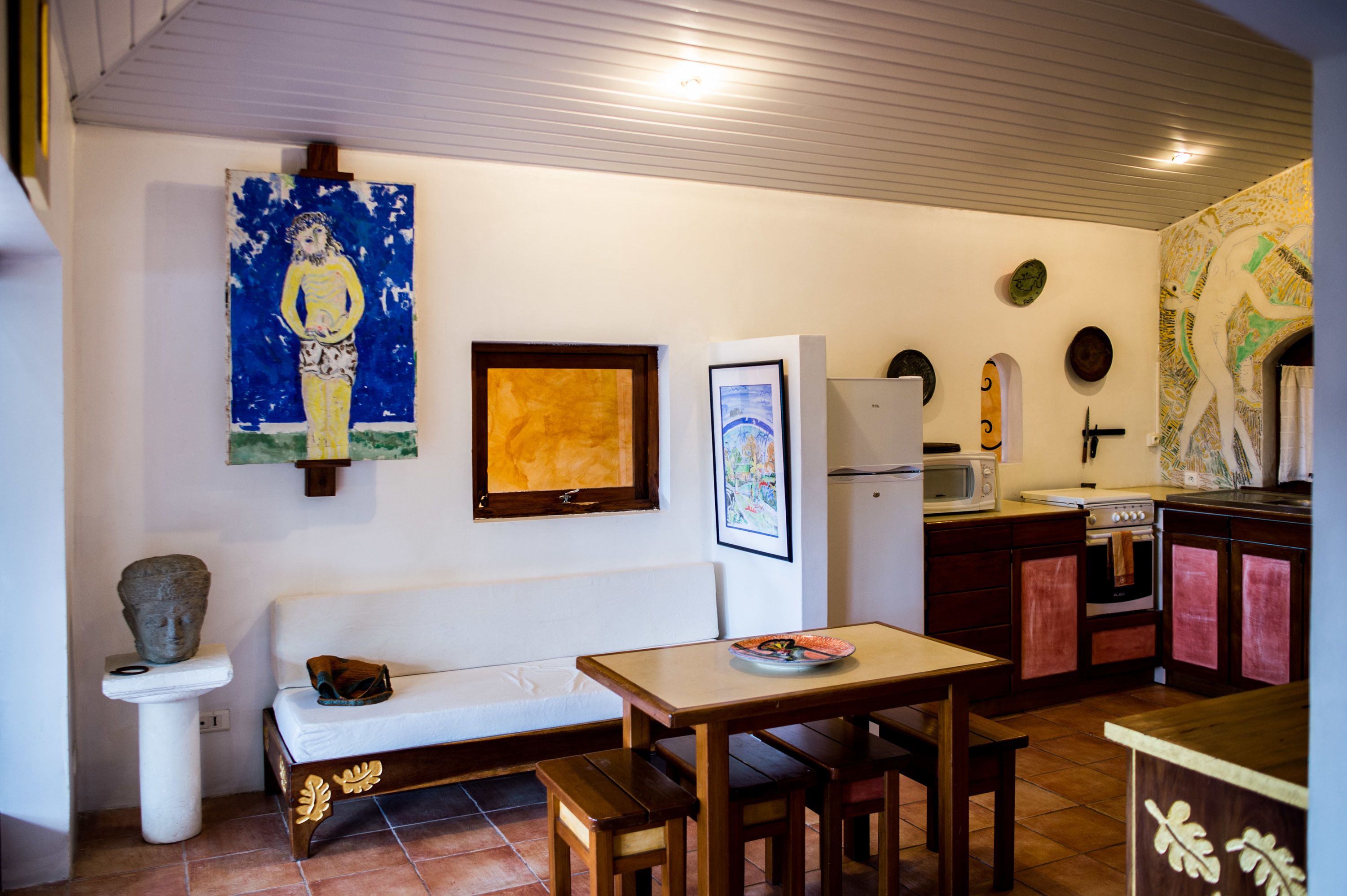 Une cuisine compacte avec un coin repas, un canapé blanc et un tableau accroché au mur.