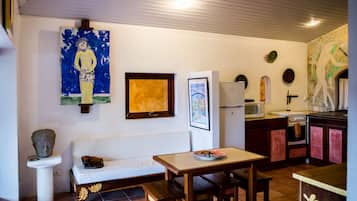 Une cuisine compacte avec un coin repas, un canapé blanc et un tableau accroché au mur.