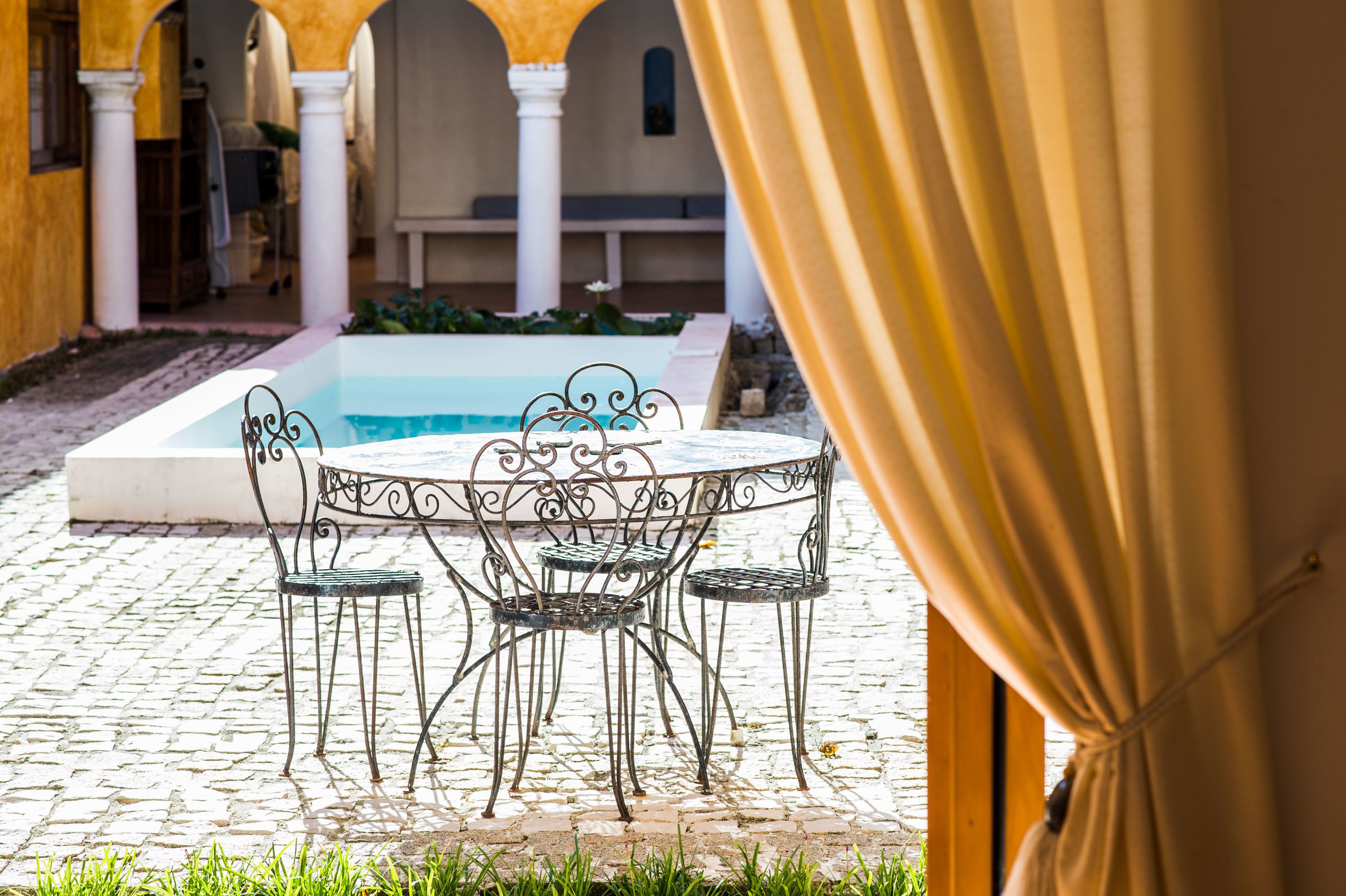 A courtyard with a pool, outdoor seating, and a view of a building in the background.