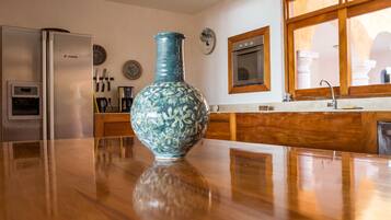 Une cuisine dotée d’un plan de travail en bois, d’un réfrigérateur en acier inoxydable, d’un vase bleu et d’une fenêtre donnant sur des colonnes architecturales.