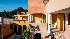 Un patio con piscina, una estatua y una montaña al fondo.