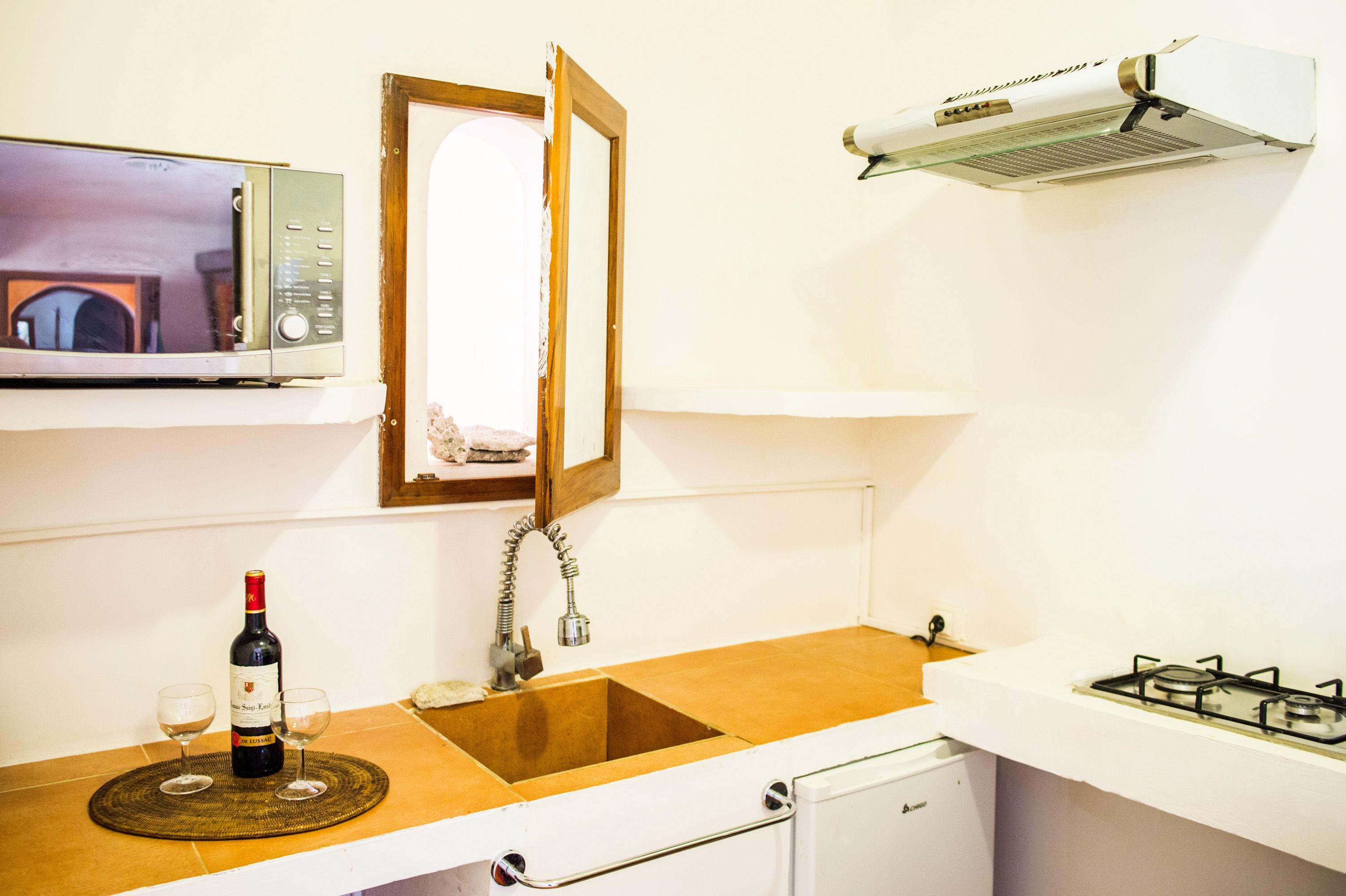 Una cocina equipada con microondas, pileta y estufa a gas.