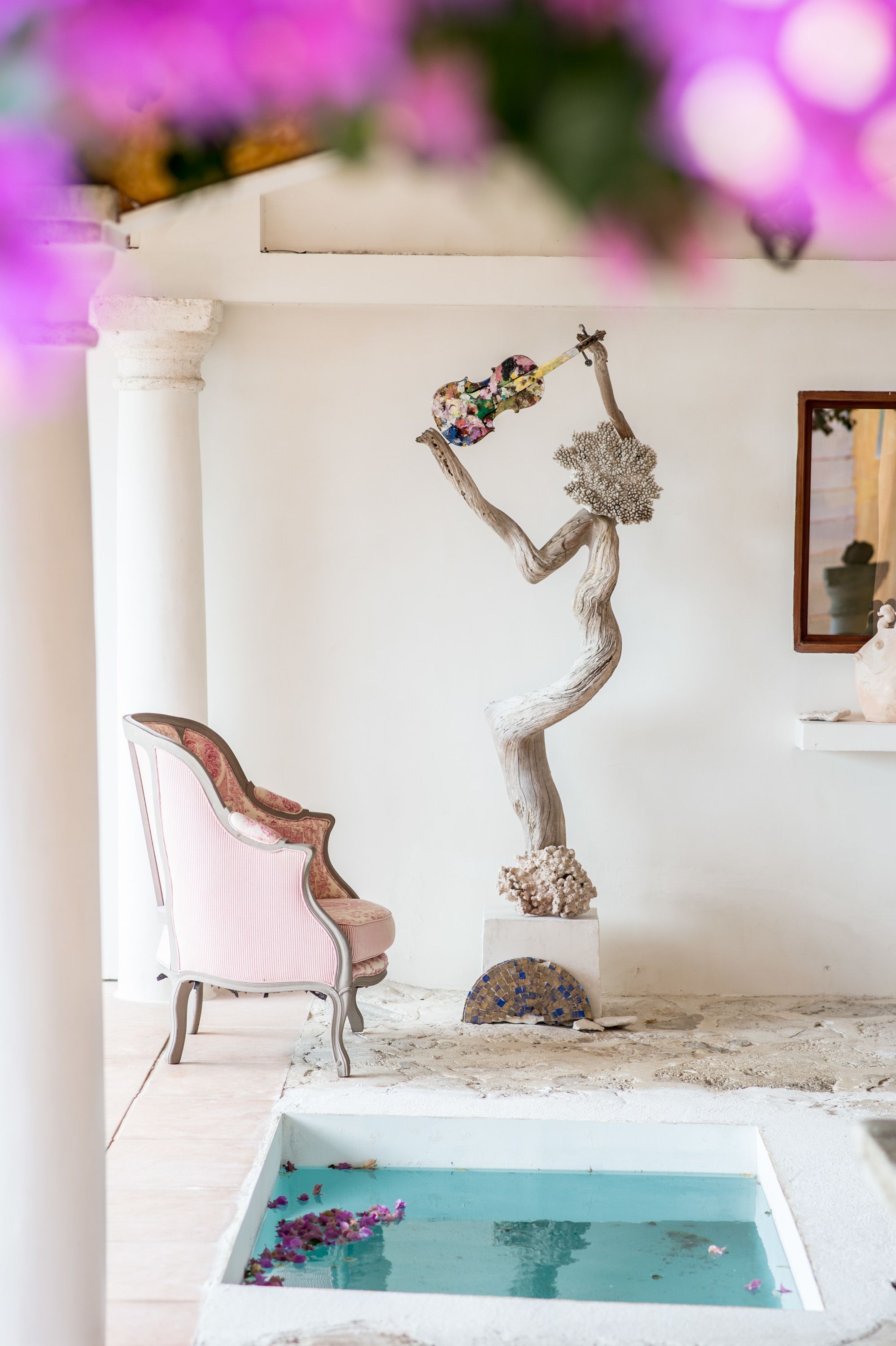 A room with a white chair, a small table, and a decorative sculpture.