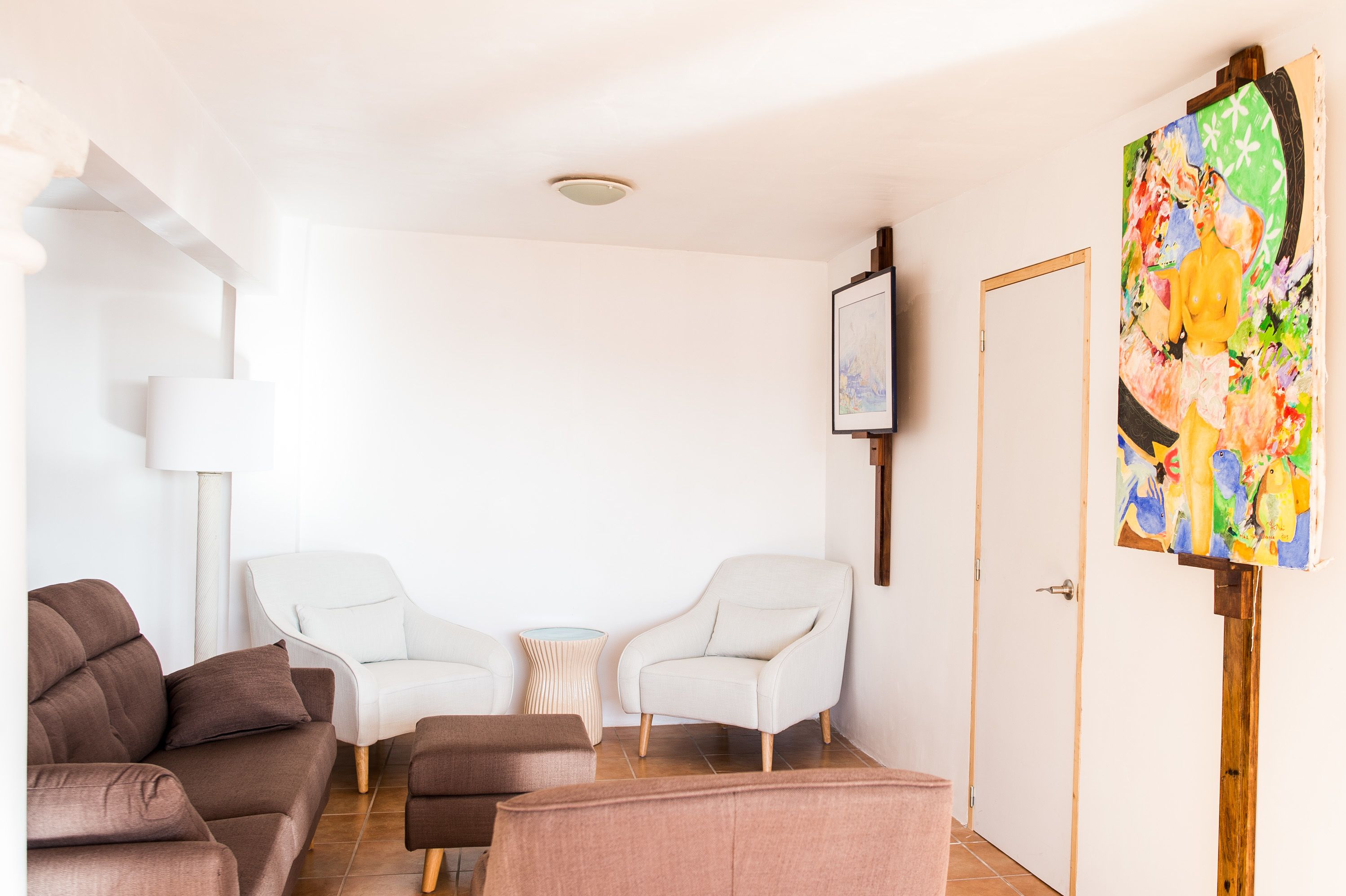 Una sala de estar moderna con un sofá, dos sillones, una mesa de centro y un cuadro en la pared.