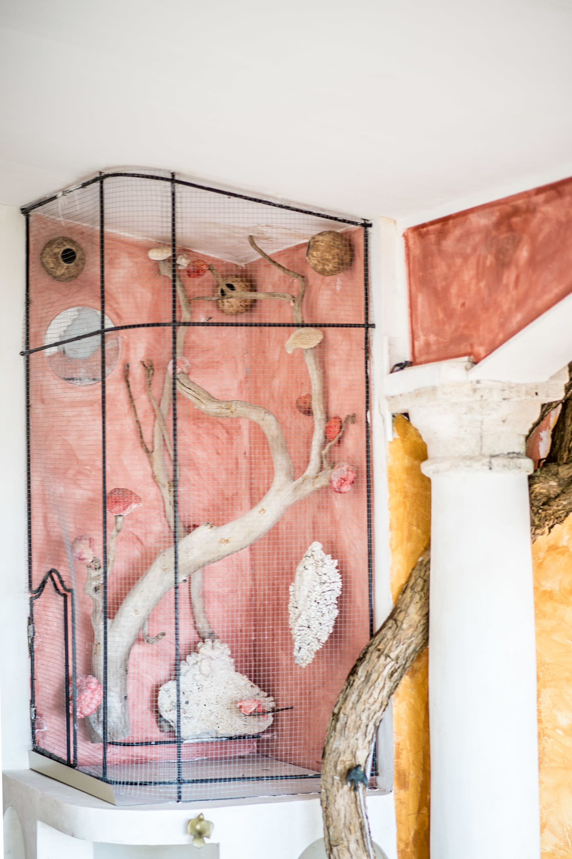 A room with a large window, a white column, and a pink wall.