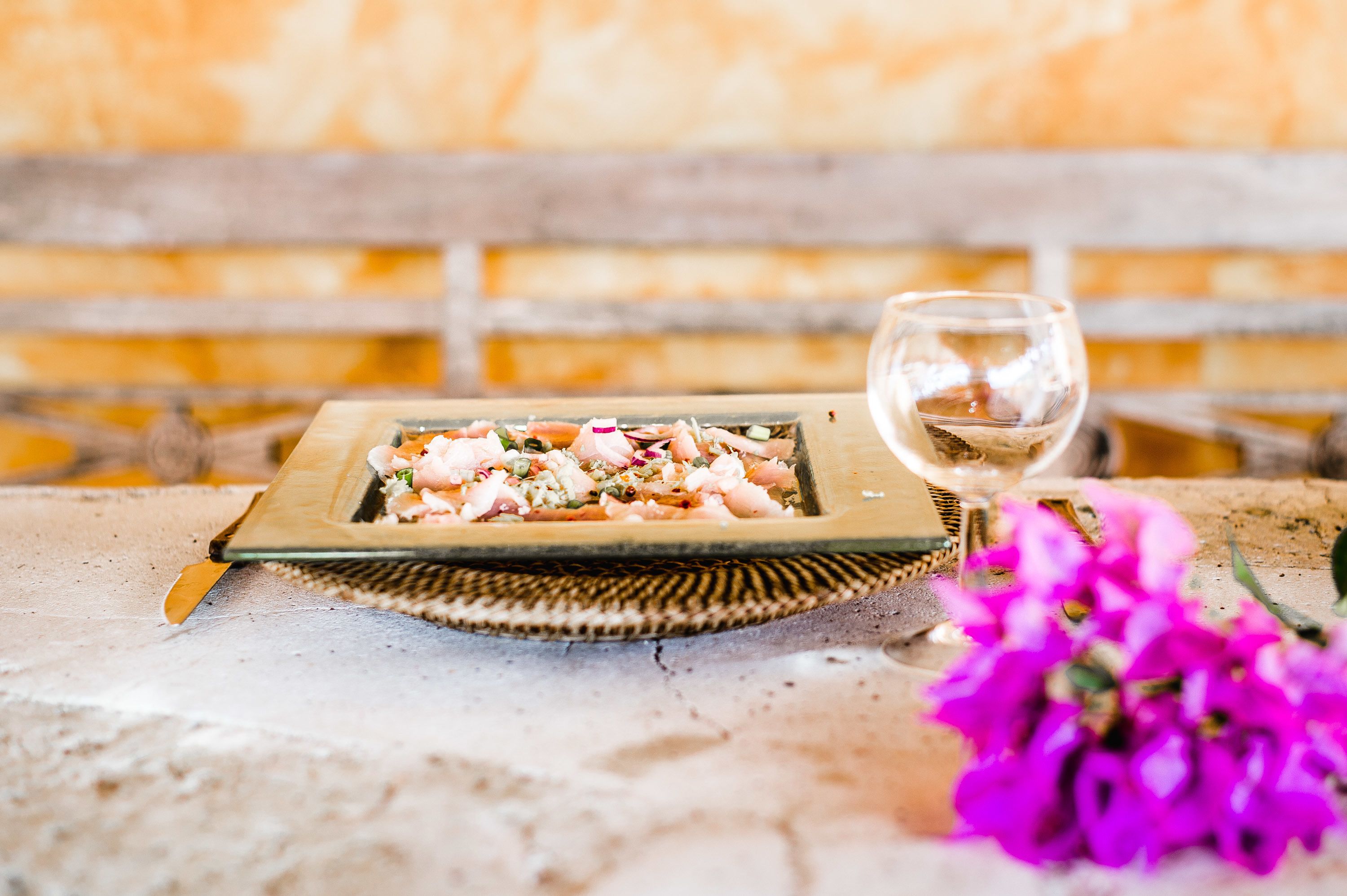 A wooden table with a plate of food and a glass of wine.
