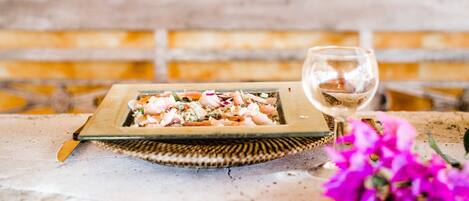 A wooden table with a plate of food and a glass of wine.