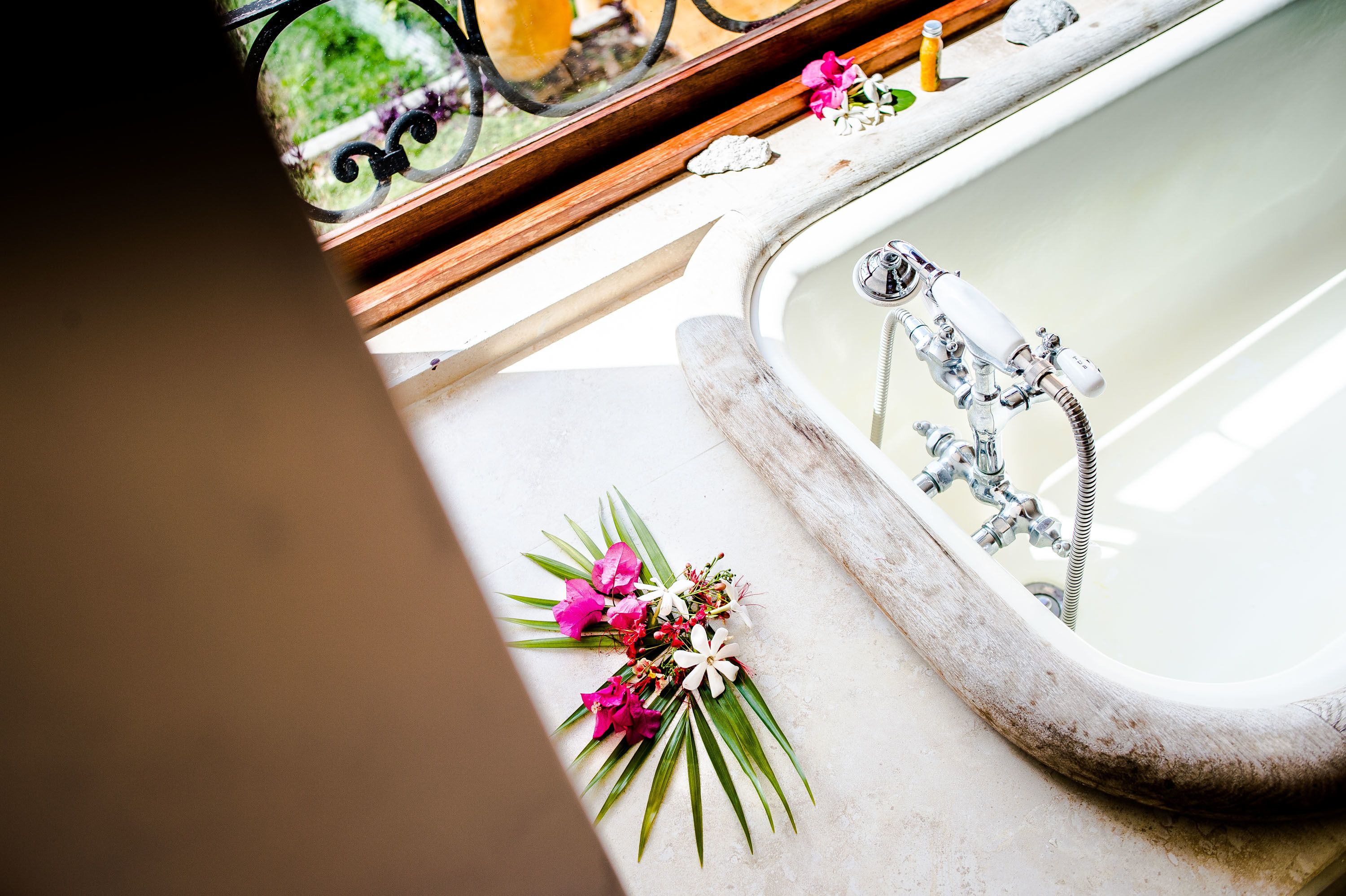 A bathtub with a wooden frame and a floral arrangement beside it.