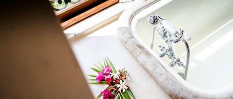 A bathtub with a wooden frame and a floral arrangement beside it.