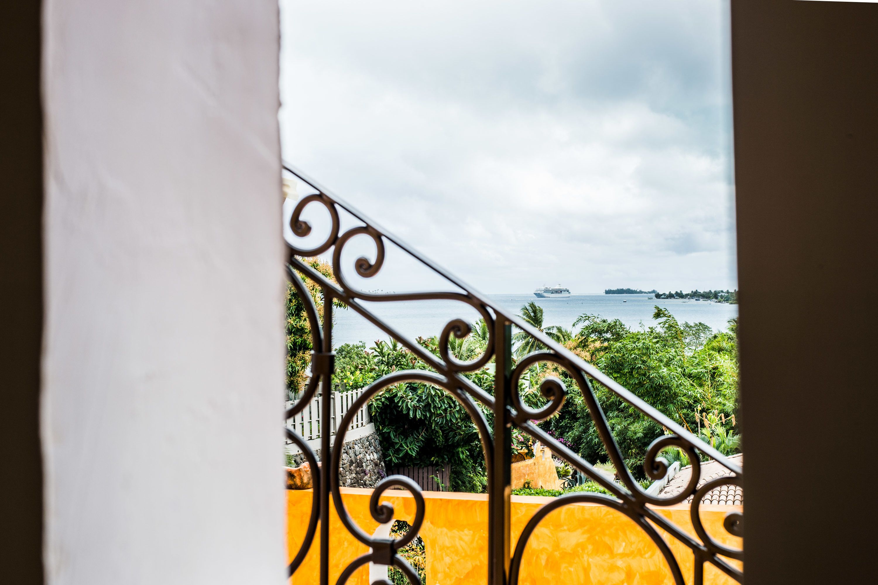 A balcony with a wrought iron railing overlooking a body of water and greenery.