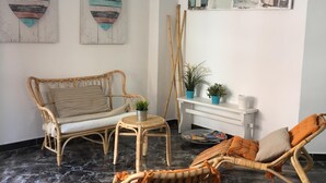 A room with a rattan sofa, a wicker chair, a small table with a plant, and a wall with artwork. - Cosy house in small fishing village away of crowds (El Tablado, Güímar)