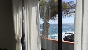 A window with sheer curtains, a view of the ocean, and a palm tree. - Cosy house in small fishing village away of crowds (El Tablado, Güímar)