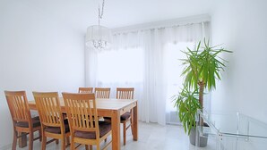 Een eetgedeelte met een houten tafel en stoelen, een bloempot en een glazen balustrade.