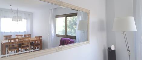A hotel room with a dining table and chairs, a large mirror, a bed, and a floor lamp.