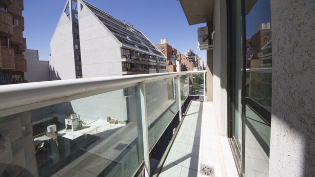 A modern building with a glass balcony and a metal railing.