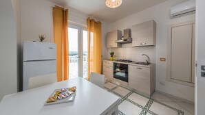 Eine moderne Küche mit Kühlschrank, Herd, Backofen und Spüle. Ein Esstisch mit einer Schale Essen.