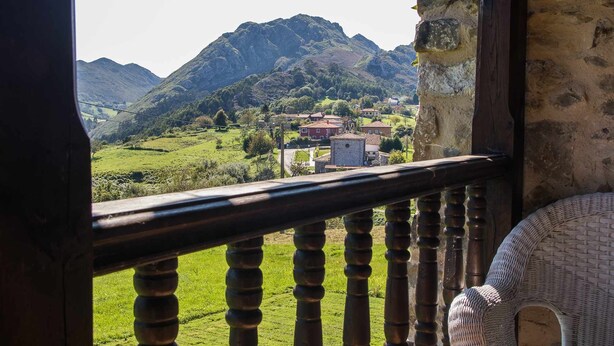 A balcony with a view of a village and mountains.