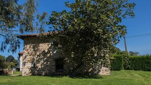 A stone building with a small window and a door, surrounded by a well-maintained lawn and trees.