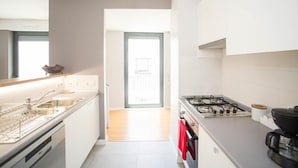 A modern kitchen with white cabinets, a gas stove, a dishwasher, and a hanging pendant light. - Central Lisbon - Downtown | AC | Wi-Fi | Elevator & Garage (Lisboa)