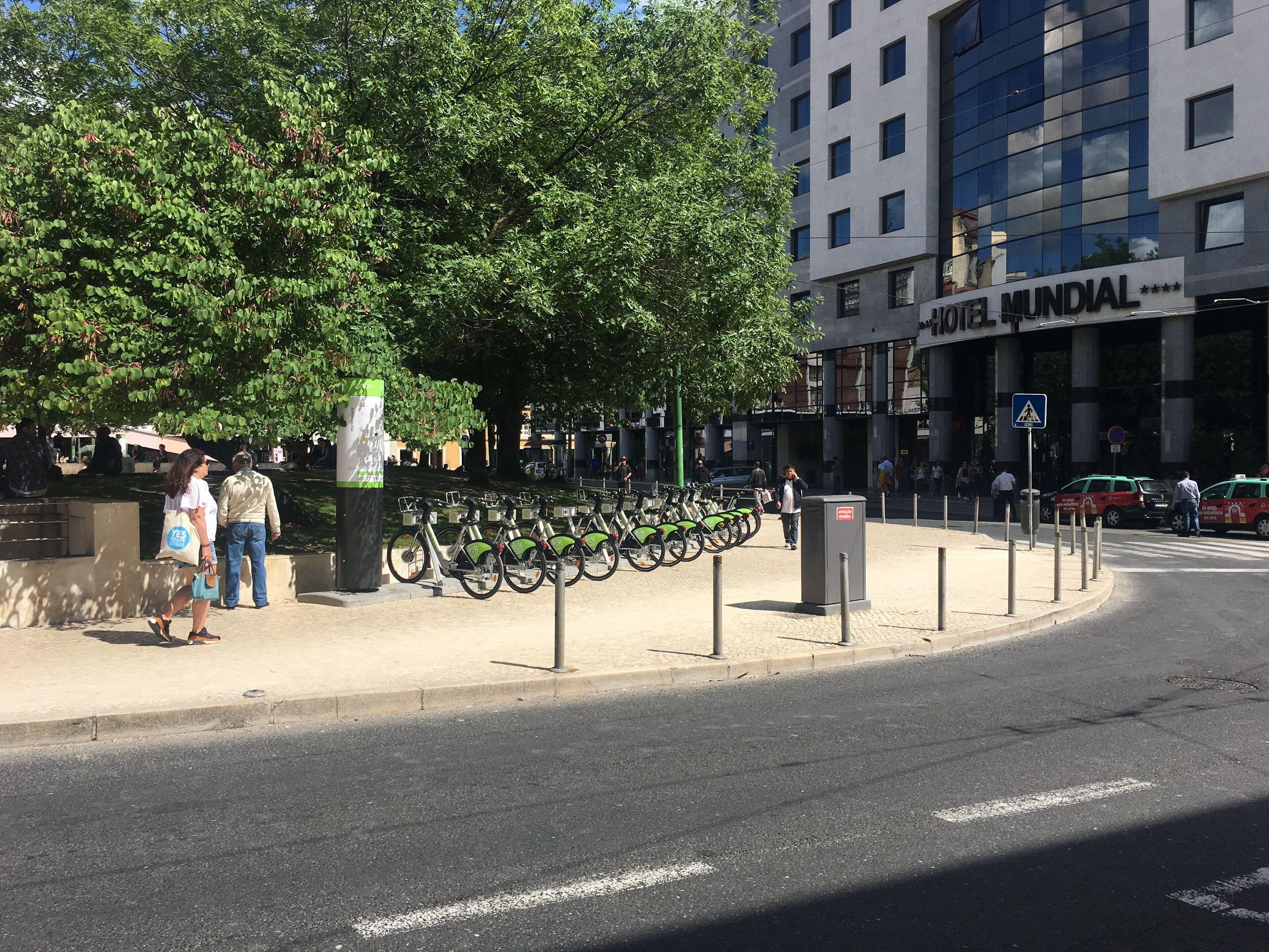 Een stadstraat met een fietsenstalling, een voetgangersoversteek en een gebouw met de tekst 'MUNDIAL'.