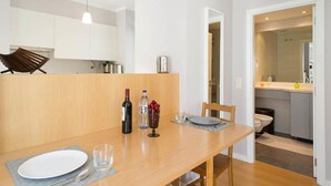 A modern kitchen with white cabinets, a dining table set with plates, glasses, and a bottle of wine. - Central Lisbon - Downtown | AC | Wi-Fi | Elevator & Garage (Lisboa)