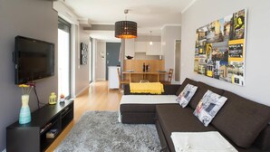 A modern living room with a flat-screen TV, a sofa, a coffee table, and a dining area in the background. - Central Lisbon - Downtown | AC | Wi-Fi | Elevator & Garage (Lisboa)
