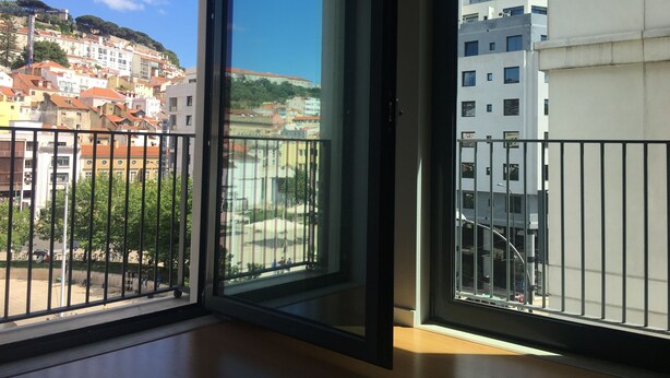 A balcony with a view of a cityscape, including buildings and a hill. - Central Lisbon - Downtown | AC | Wi-Fi | Elevator & Garage (Lisboa)