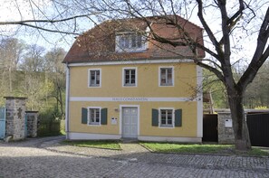 Ein zweistöckiges Gebäude mit einer gelben Fassade, einem roten Ziegeldach und einem Schild mit der Aufschrift 'HAUS CONSTANTIN'.