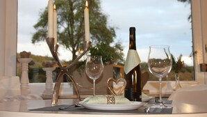 Une table dressée pour deux personnes, avec des bougies, des verres à vin et une bouteille de vin.