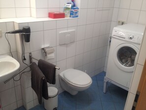 Een bad/douchecombinatie, een haardroger, handdoeken, zeep