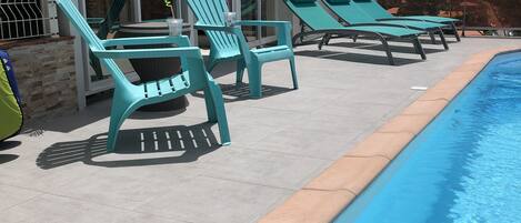 Un espace aménagé au bord de la piscine, avec des chaises longues et un coin salon abrité.