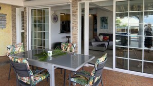 A patio area with a glass table and chairs, a brick floor, and a sliding glass door leading to a living room. - Superb views - Private spa, pool and pool house. Romanticism and luxury -Trois Ilets.  (les Trois Ilets)