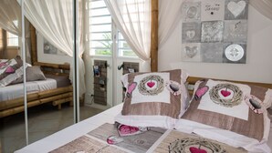 A bedroom with a bed, a mirror, and a wall decorated with heart-shaped items. - Superb views - Private spa, pool and pool house. Romanticism and luxury -Trois Ilets.  (les Trois Ilets)