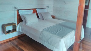 Un lit simple avec une tête de lit en bois, une table de chevet et une petite boîte en bois.