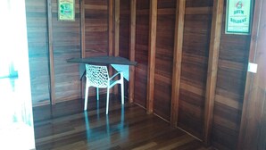 Une pièce d’angle avec des murs en bois, une petite table et une chaise. Il y a des panneaux sur les murs.
