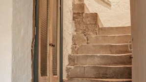 A staircase with stone steps leading upwards, a door with a metal handle, and a textured wall.