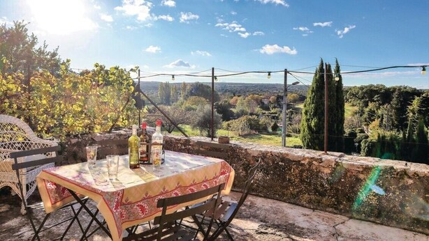 An outdoor dining area with a table set for two, overlooking a scenic landscape.