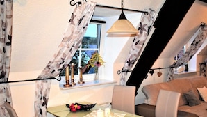 Ein gemütliches Schlafzimmer im Loft-Stil mit Essbereich, einer Couch und einem Fenster mit Vorhängen.