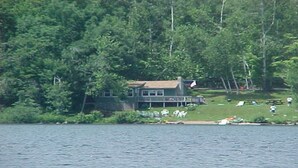 A lakeside cabin with a deck, surrounded by dense forest. - 4 Season Secluded Lakefront Home near Ski Mountains  (Mt Holly)