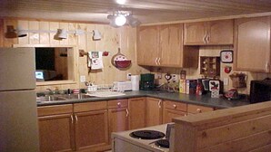 A kitchen with wooden cabinets, a stove, a sink, and various appliances. - 4 Season Secluded Lakefront Home near Ski Mountains  (Mt Holly)